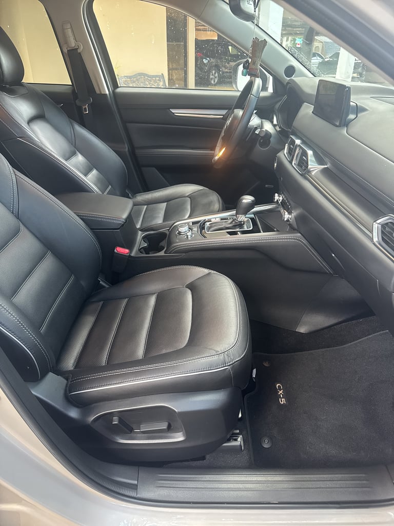 Interior view of a modern SUV with black leather seats, steering wheel, and center console visible through open door
